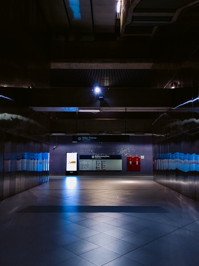 Empty dark corridor with mirrored walls and and tiled floor in modern underground station with digital monitor